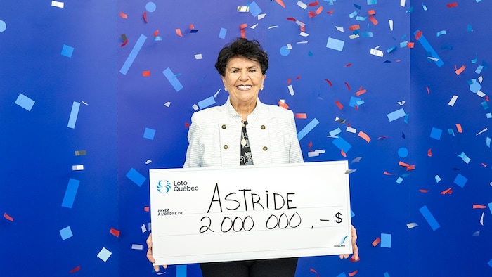 Une femme montre un gros chèque en carton pour illustrer son prix.
