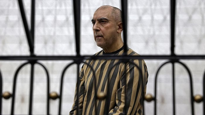 Atef Najib derrière des barreaux dans un palais de justice.