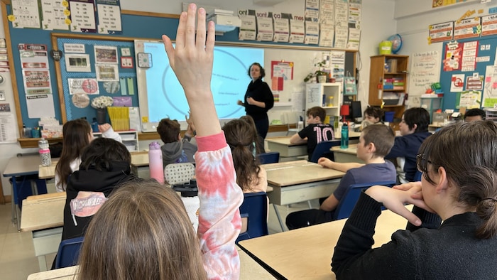 Une élève lève la main dans une classe.