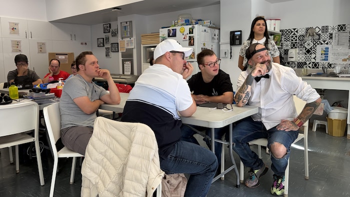 Des personnes assises autour d'une table écoutent attentivement une présentation.