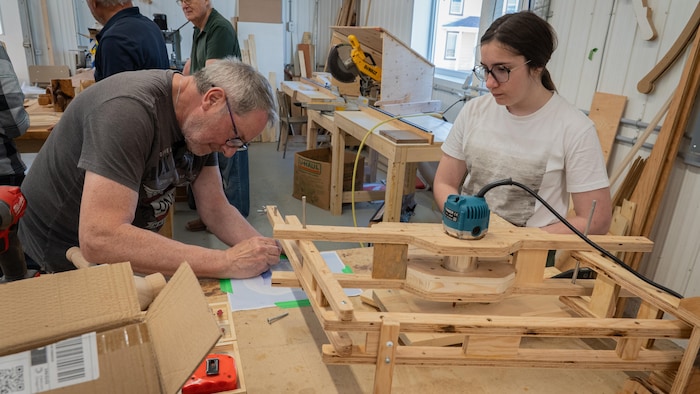 Un homme et une femme travaillent sur un morceau de bois.