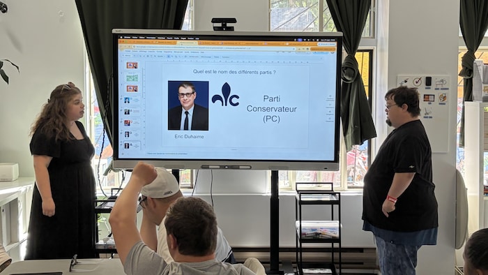 Deux personnes devant un tableau interactif.