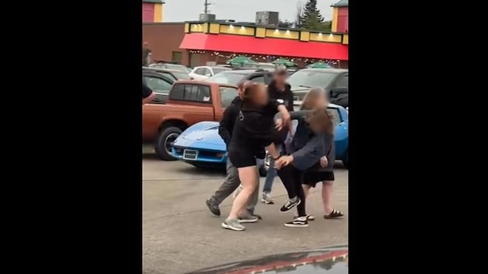 Des personnes en train de se battre dans un stationnement.