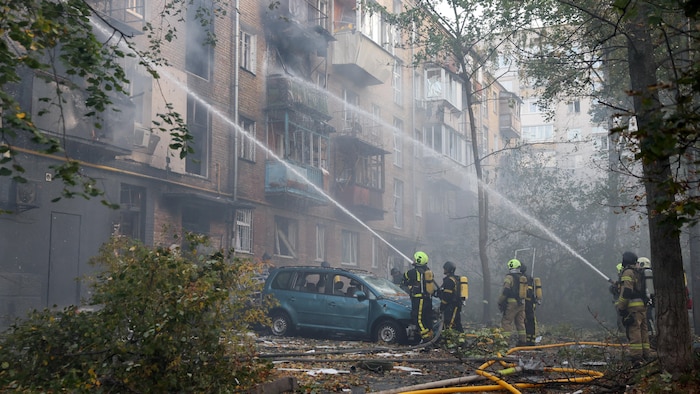 Des pompiers interviennent sur le site d'un immeuble d'habitation endommagé lors d'une frappe de drone russe à Kiev le 7 octobre 2026.