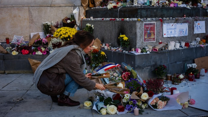 Elle se penche devant le mémorial pour déposer des fleurs.