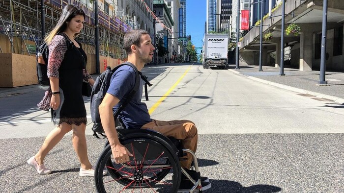 Un jeune homme se déplace en fauteuil roulant au centre-ville de Vancouver. 