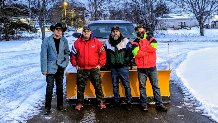 Quatre gars en avant d'une déneigeuse. 
