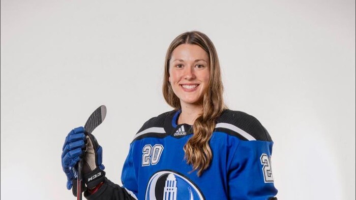 Une joueuse de hockey sourit.