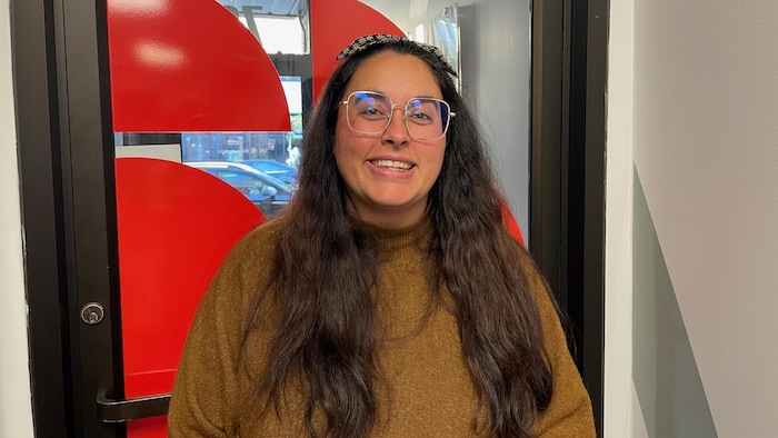 Audrey Desrochers pose devant la porte des bureaux de Radio-Canada.