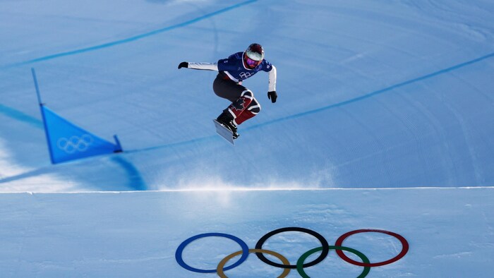 Elle fait un saut sur le parcours de snowboard cross.