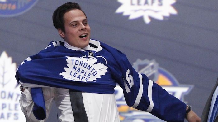 Auston Matthews enfile le chandail des Maple Leafs sur la scène après avoir été repêché par l'équipe.
