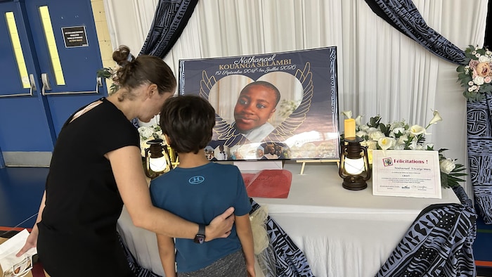 Un enfant observe un autel à la mémoire de Nathanael accompagné d'une femme.