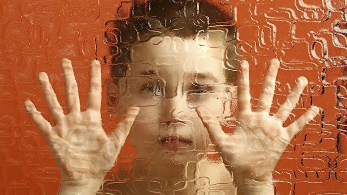 Un enfant prisonnier derrière une paroi translucide. 