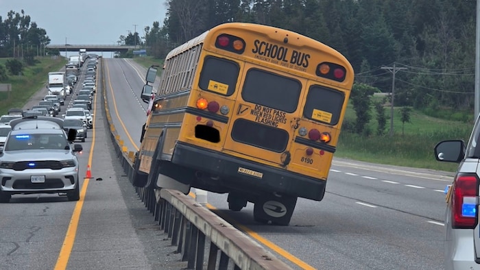 Deux des roues de l'autobus sont coincées sur la barrière médiane.