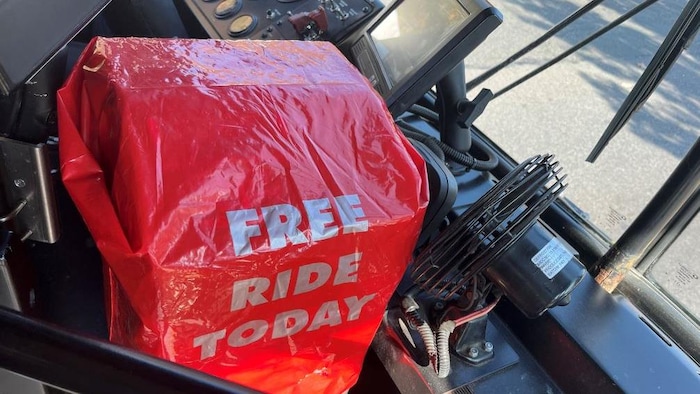 Une boîte de validation de titres dans un autobus recouverte d'une housse rouge sur laquelle on peut lire «Free ride today», ou «Passage gratuit aujourd'hui».