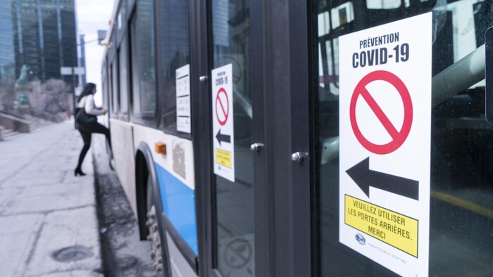 Une pancarte sur la porte avant d'un autobus demande aux usagers d'« utiliser les portes arrières ».