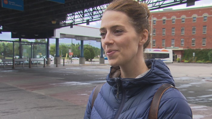 Une femme parle dans un terminus d'autobus extérieur.