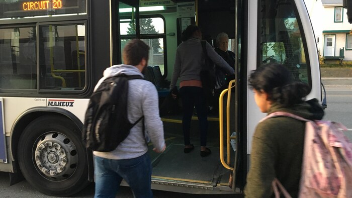Deux personnes à côté d'un autobus s'apprêtent à embarquer.