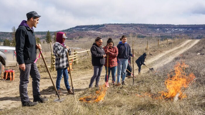 Une dizaine de personnes mettent le feu à des branchages secs.