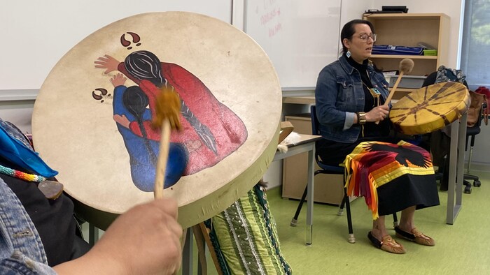 Dos mujeres indígenas tocan tambores.