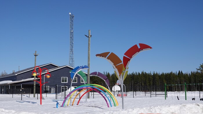 Le parc determination les enfants de la communauté sous la neige avec, en arrière, le centre communautaire.