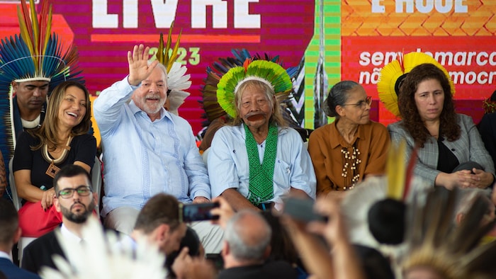 Lula cumprimenta a multidão acompanhado de três mulheres em um palanque.