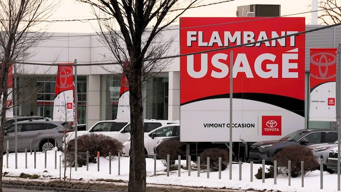 Façade et stationnement du concessionnaire Vimont Toyota avec une pancarte promotionnelle arborant le slogan « Flambant usagé ».