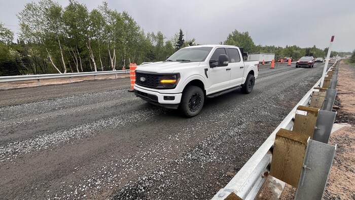 Une camionnette circule sur un tronçon de route en réfection. 