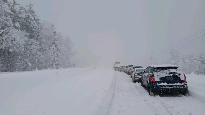 Une route enneigée et des voitures immobilisées.