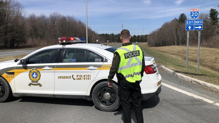 Un policier en dehors de son véhicule bloque l'autoroute 20