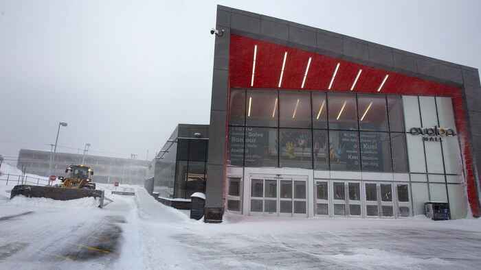 Une déneigeuse enlève la neige du stationnement d'un centre commercial.