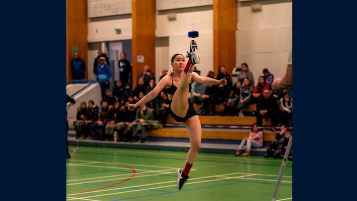 Une jeune femme touchant presque la balle accrochée en hauteur.