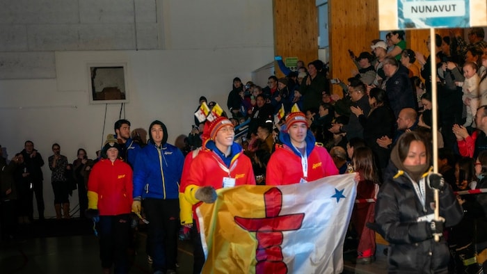 La délégation du Nunavut défilant fièrement tenant leur drapeau.