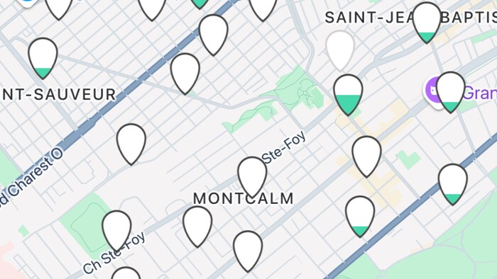 Capture d'écran de l'application mobile "à vélo" affichant une carte stylisée de la ville de Québec. Plusieurs marqueurs de localisation blancs en forme de goutte et un cercle bleu, représentant probablement des stations de vélos, sont dispersés sur la carte.