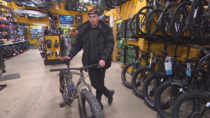 Antonin Durand debout au milieu de vélos dans un magasin de Winnipeg au Manitoba. 