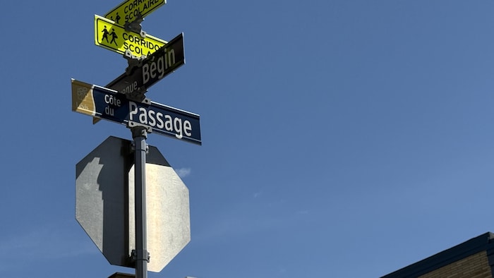 Poteaux de signalisation routière indiquant la Côte du Passage, l’avenue Bégin et un corridor scolaire sous un ciel bleu.