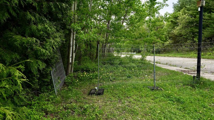 Une section de clôture métallique ouverte devant une rue.