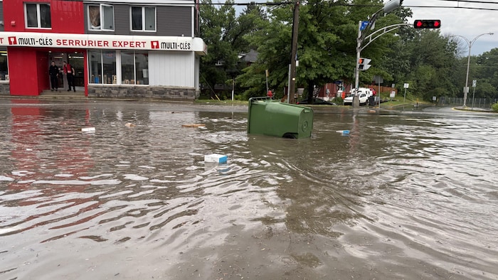 Une poubelle et des déchets flottent sur l'eau.
