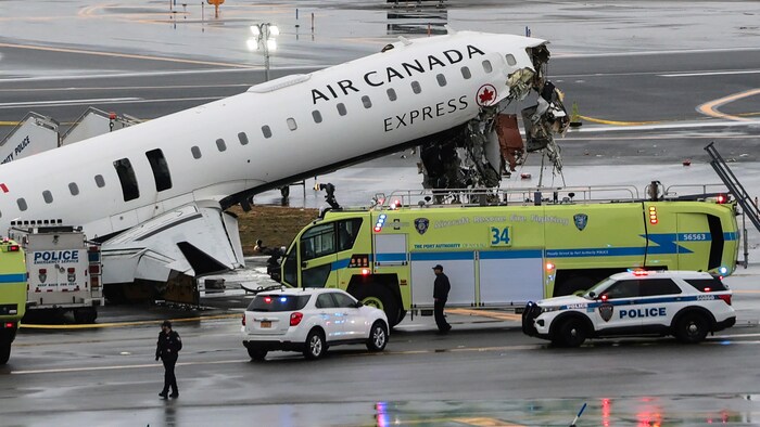 Des services d'urgence autour d'un avion en morceaux.