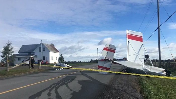 Un avion écrasé sur une route en face d'une maison.