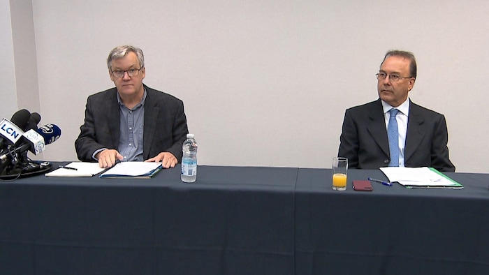 Alain Arsenault et Marc Bellemare en conférence de presse. Les deux hommes sont assis derrière une table.