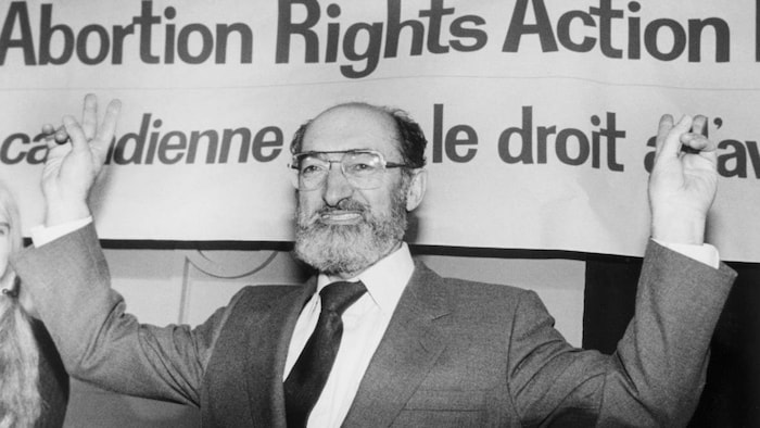 Le Dr Morgentaler se tient devant une bannière pro-choix.