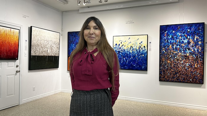 Aylin Seçkin Georges pose devant les toiles. 