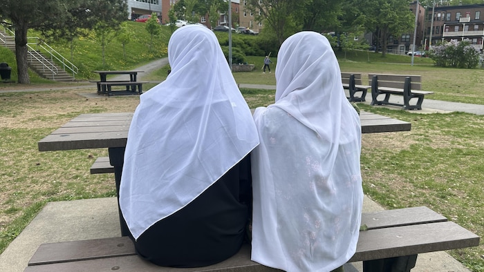 Deux femmes portant le voile intégrale assisent sur table à pique-nique.