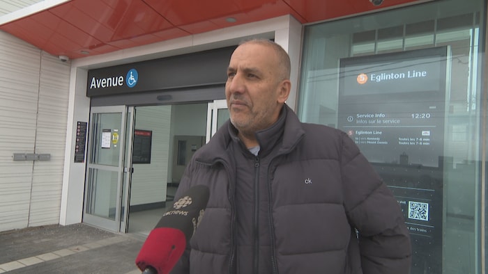 Aziz Zouargui devant une station de train en entrevue. 