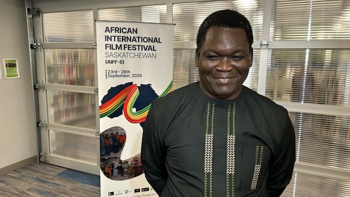 Le directeur du festival, Babatunde Onikoyi, posant devant l'affiche du festival