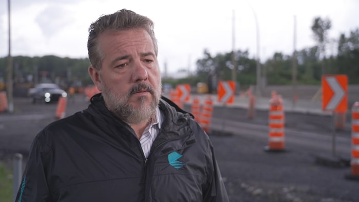 Éric Allard debout près d'un chantier routier.