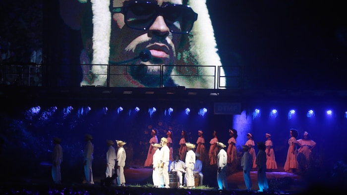 Dans une salle de spectacle, une vingtaine d'artistes dansent sur scène.