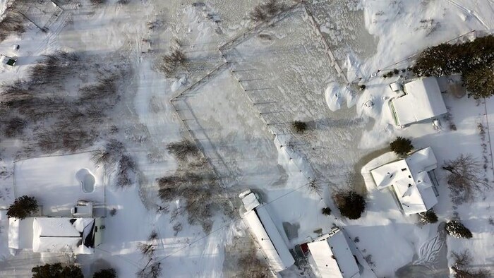 Un drone capte par image des inondations près de résidences enneigés. 