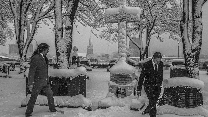 Deux hommes marchent dans la neige dans un cimetière.